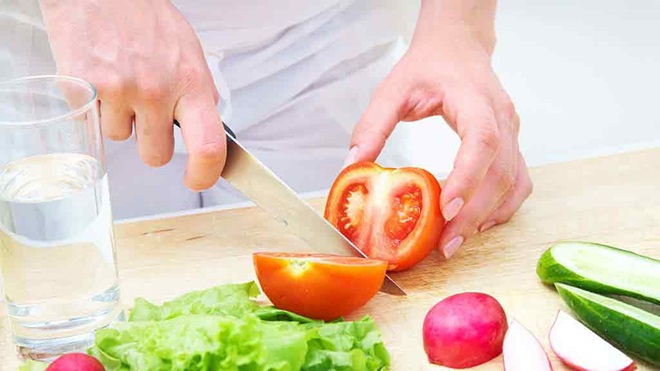 knife slicing veg on chopping board